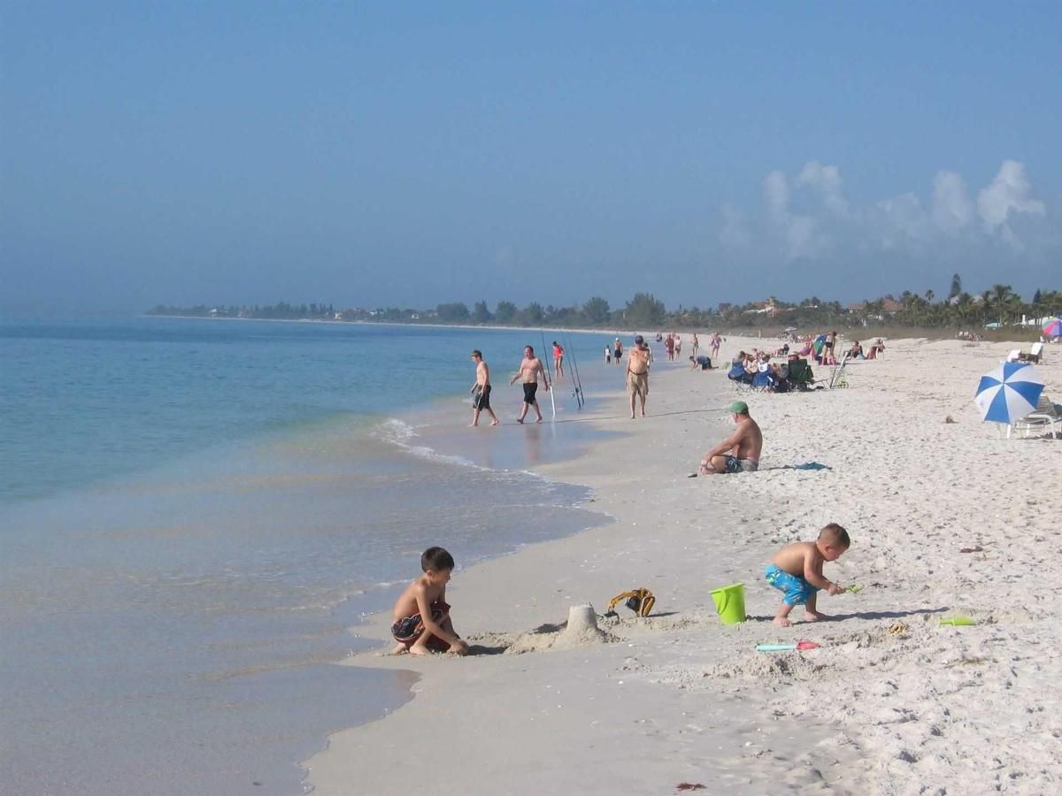 A group of people are playing in the sand on a beach