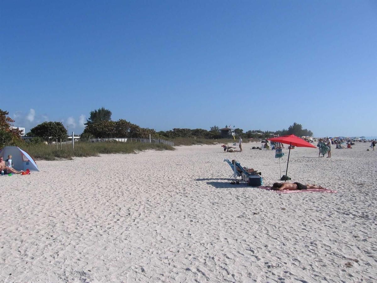 A beach with a red umbrella and a tent