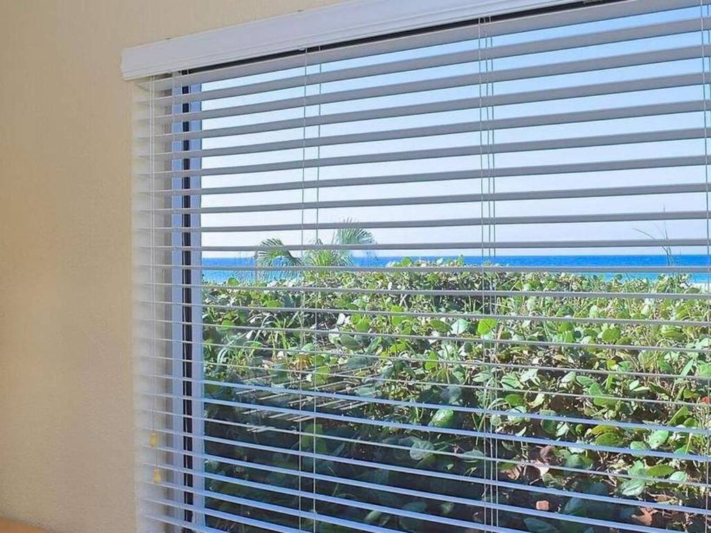 A window with blinds on it and a view of the ocean.