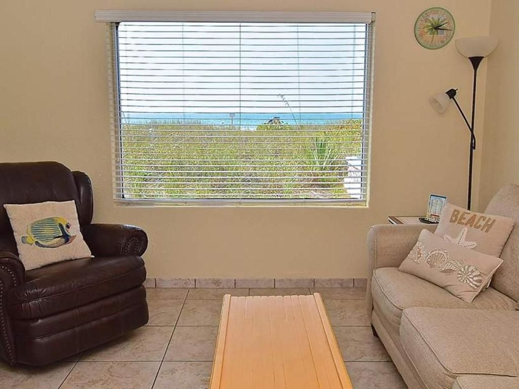 A living room with a couch , chair , coffee table and window with blinds.