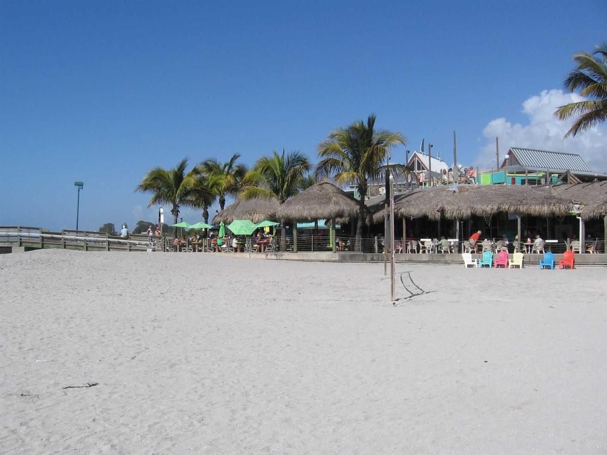 A beach with thatched huts and chairs on it