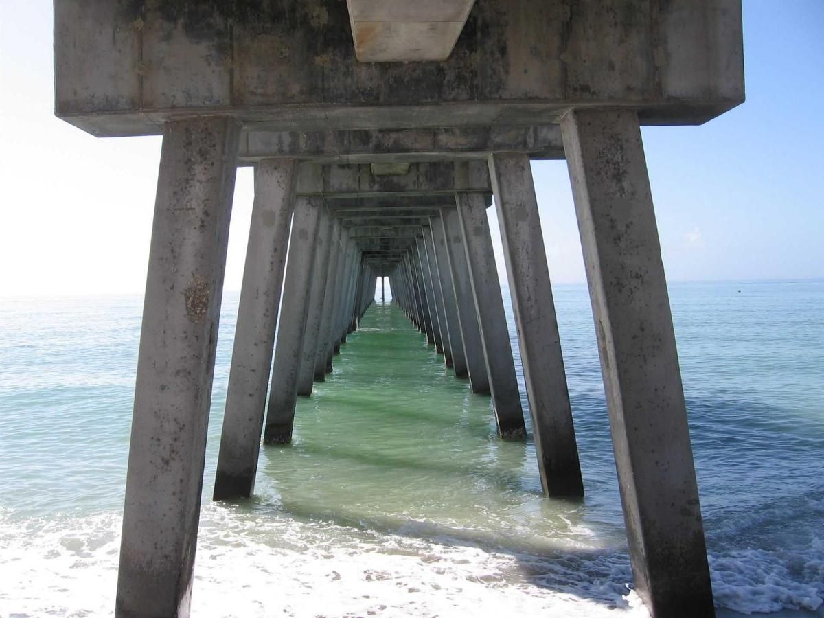 Looking down a pier into the ocean on a sunny day