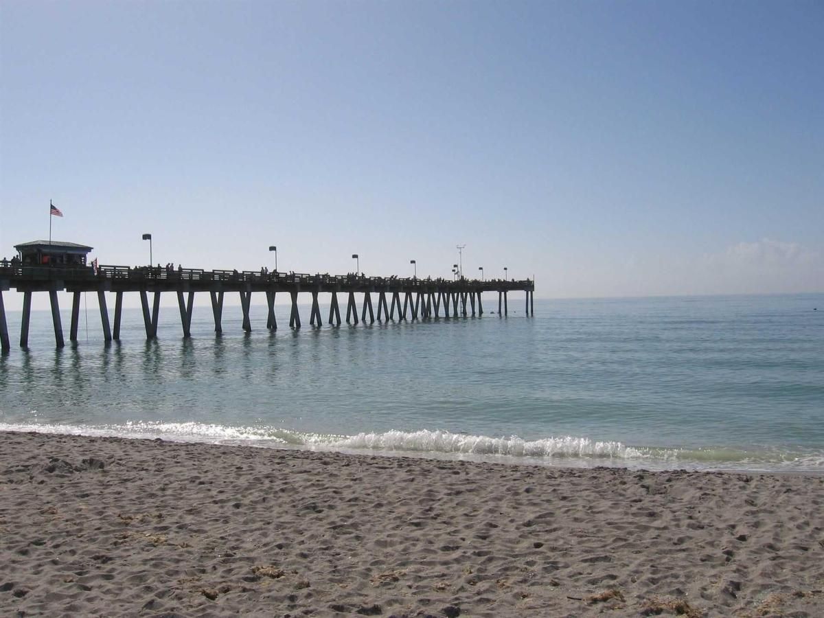 A pier on a beach with a blue sky in the background