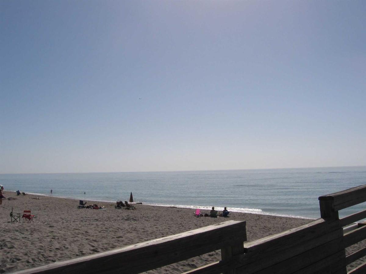 A beach with a wooden fence leading to the ocean