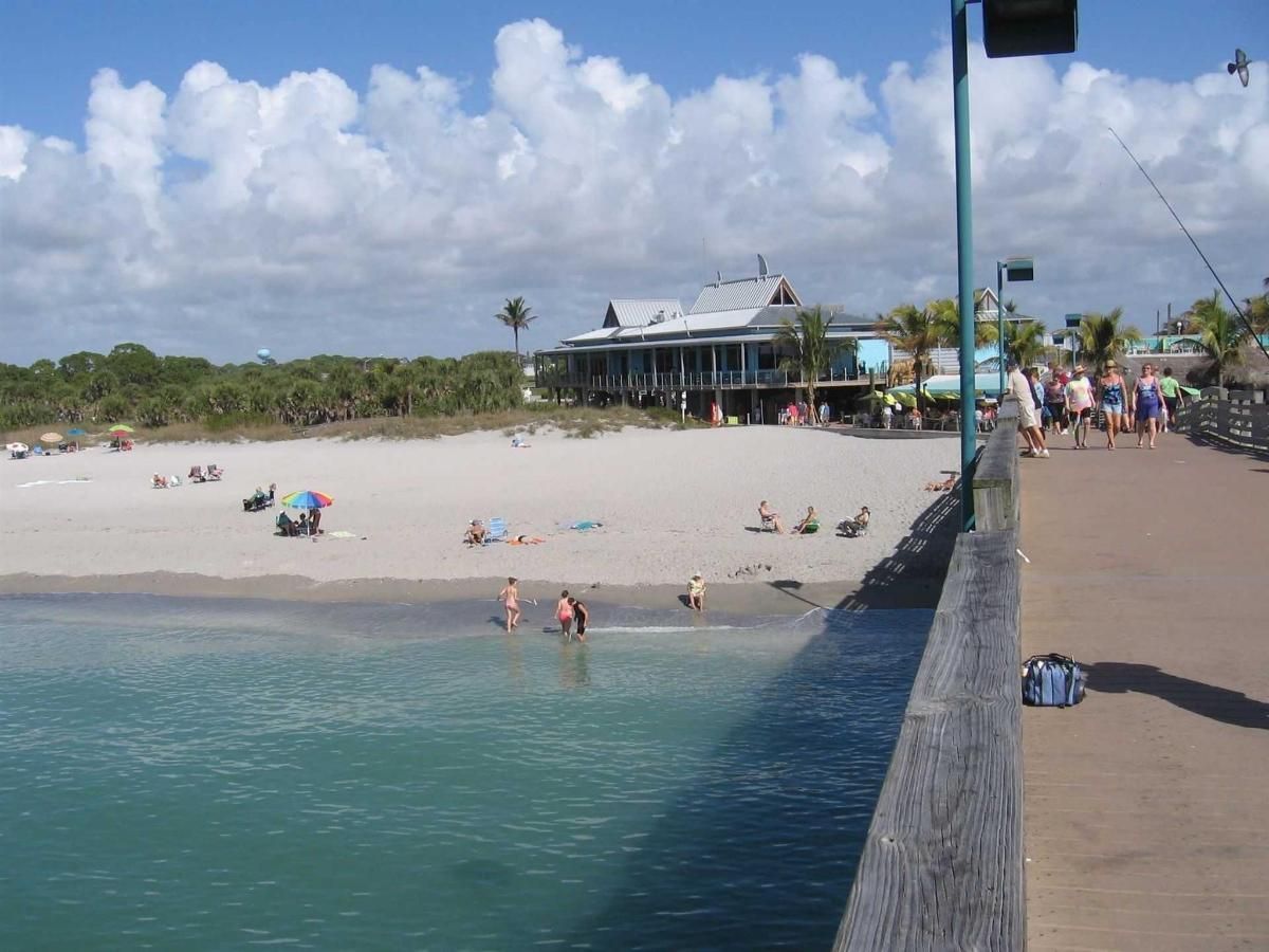 A pier leading to a beach with people on it