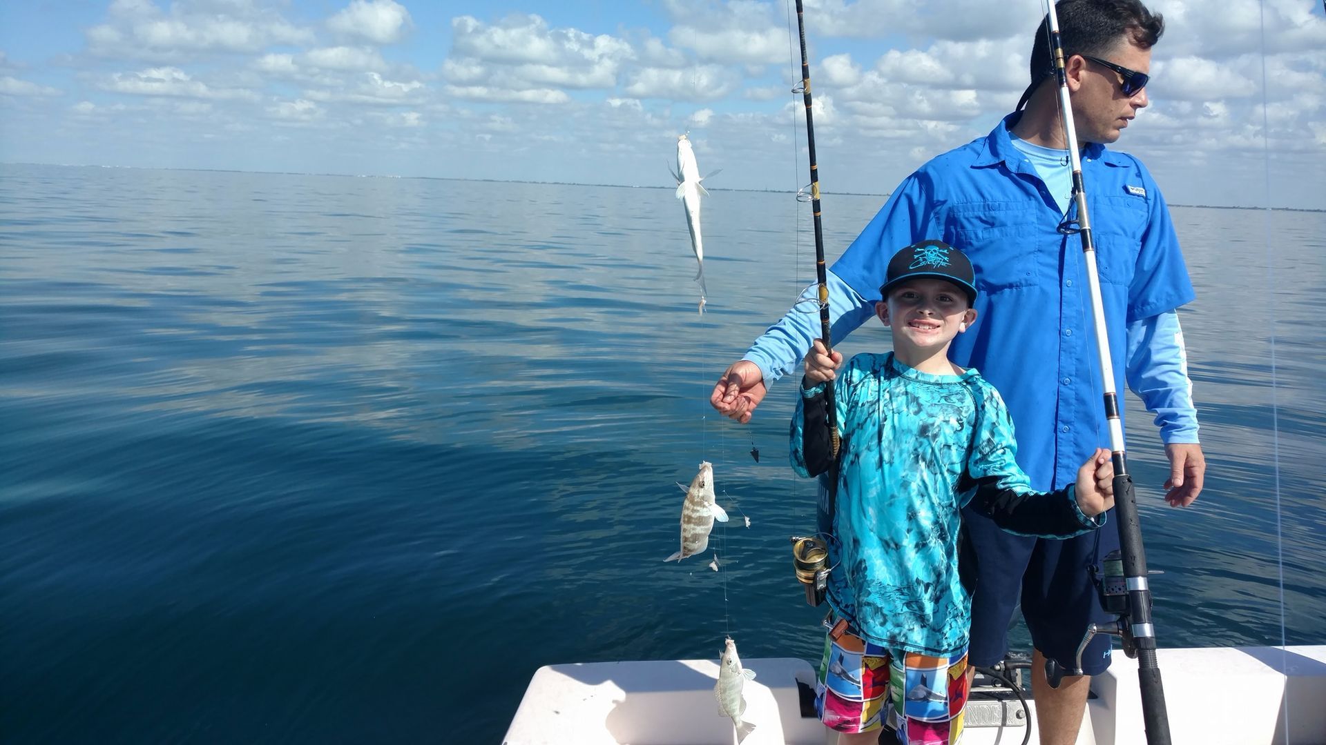 A man and a boy are fishing on a boat in the ocean.