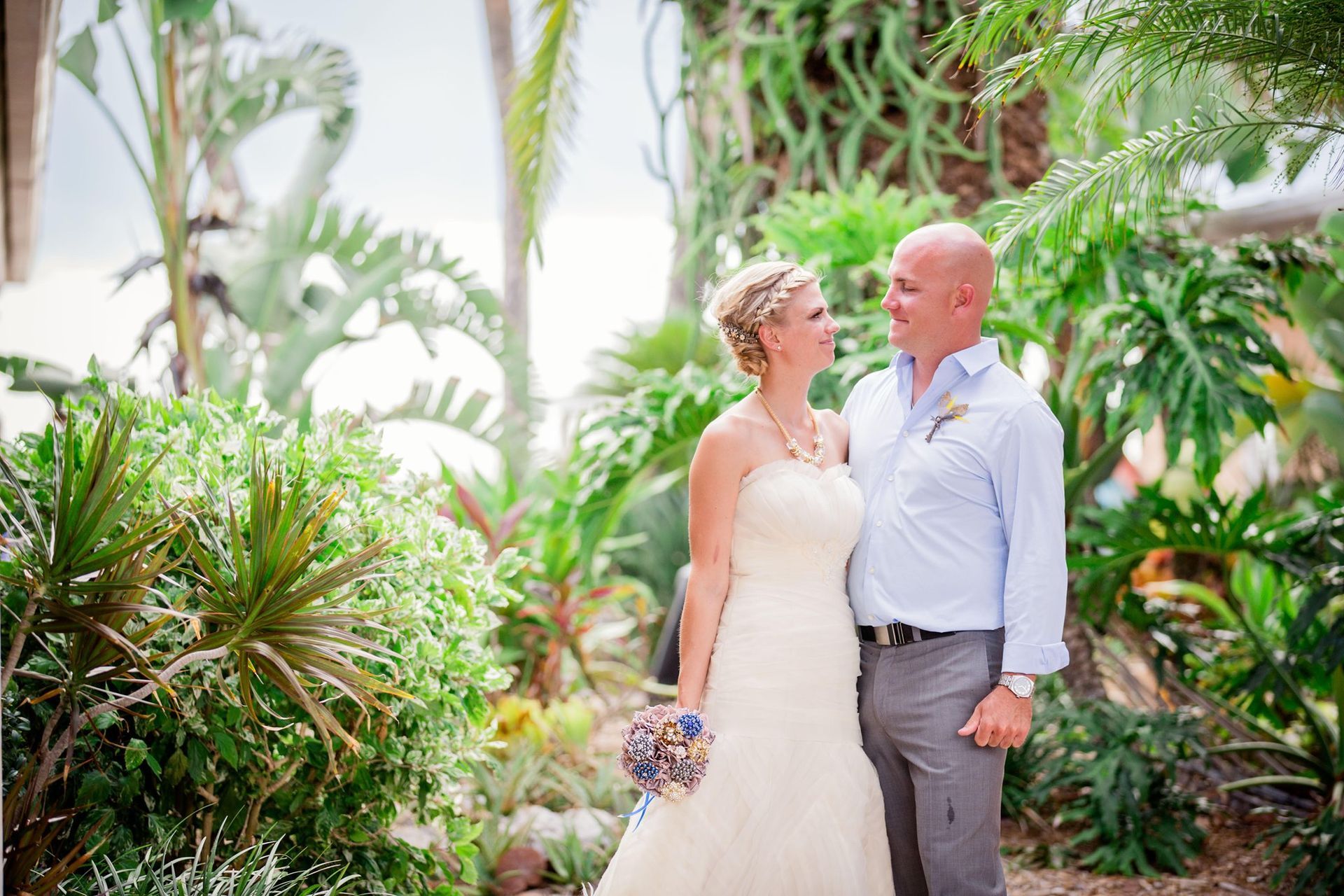 A bride and groom are standing next to each other in a garden.