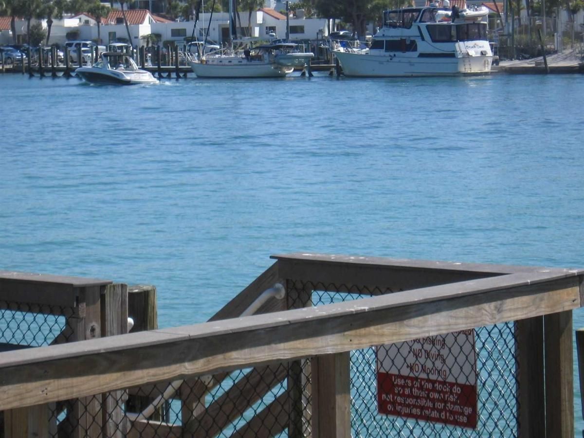 A wooden railing overlooking a body of water with boats in the background