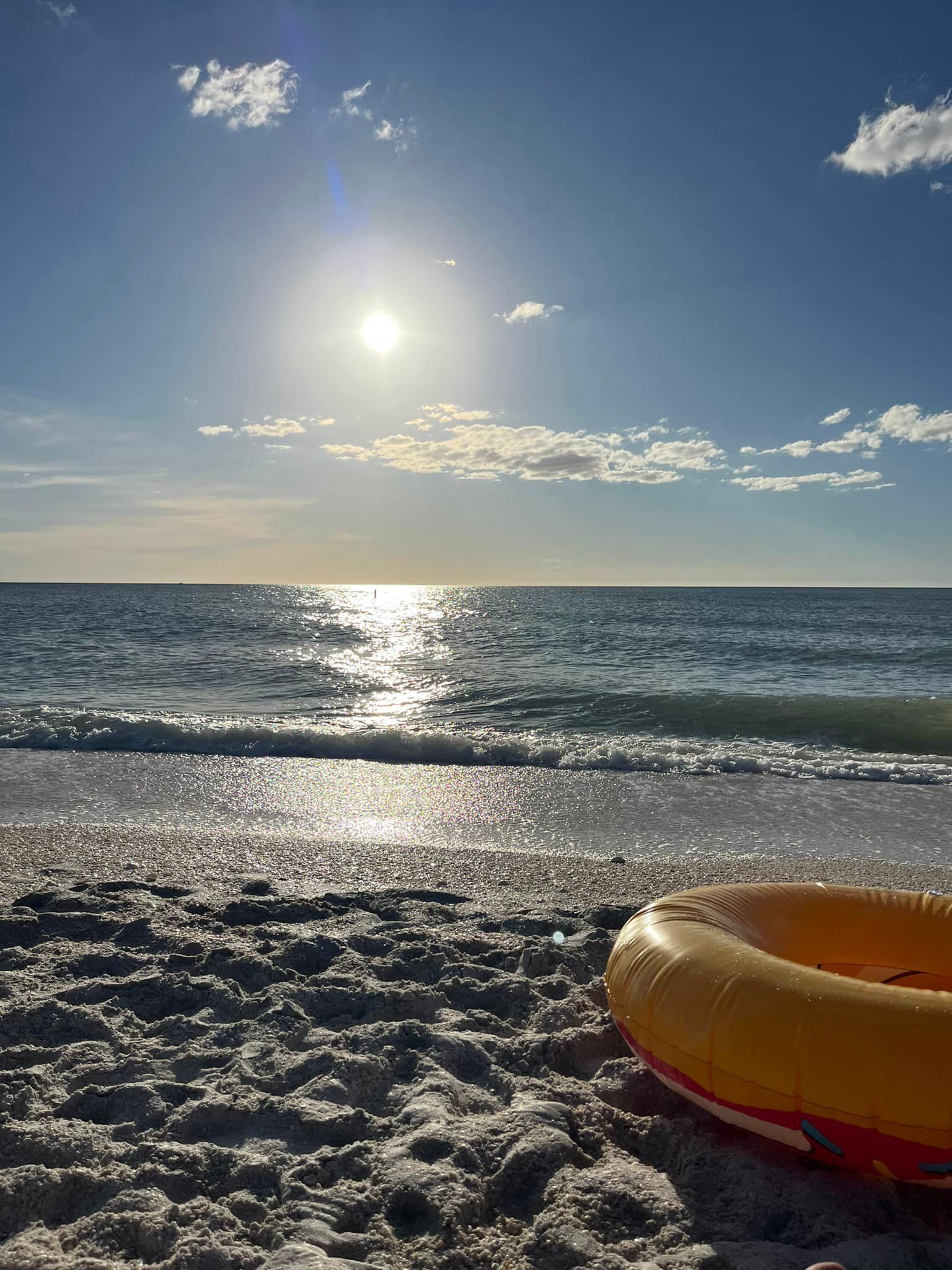 A life preserver is sitting on the beach near the ocean.