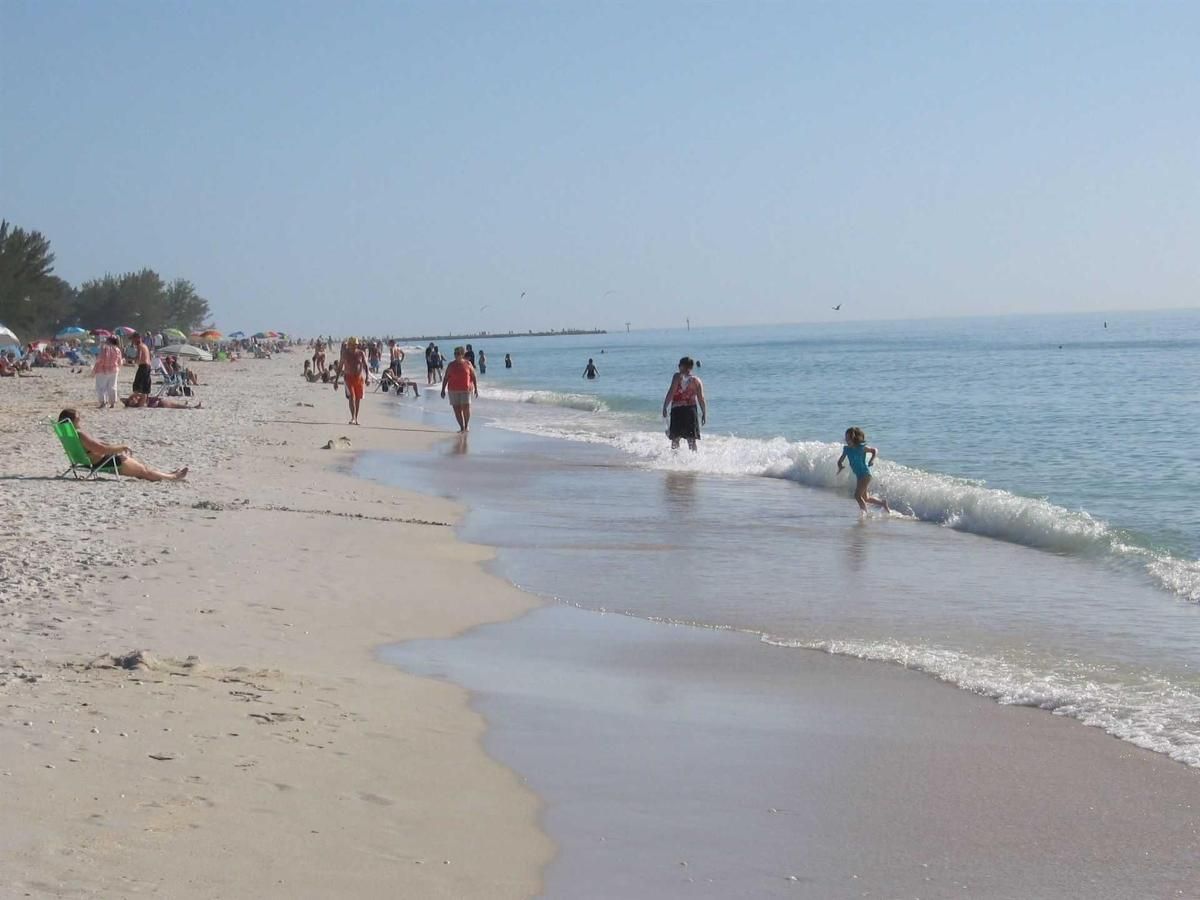 A group of people are walking on a beach near the ocean.