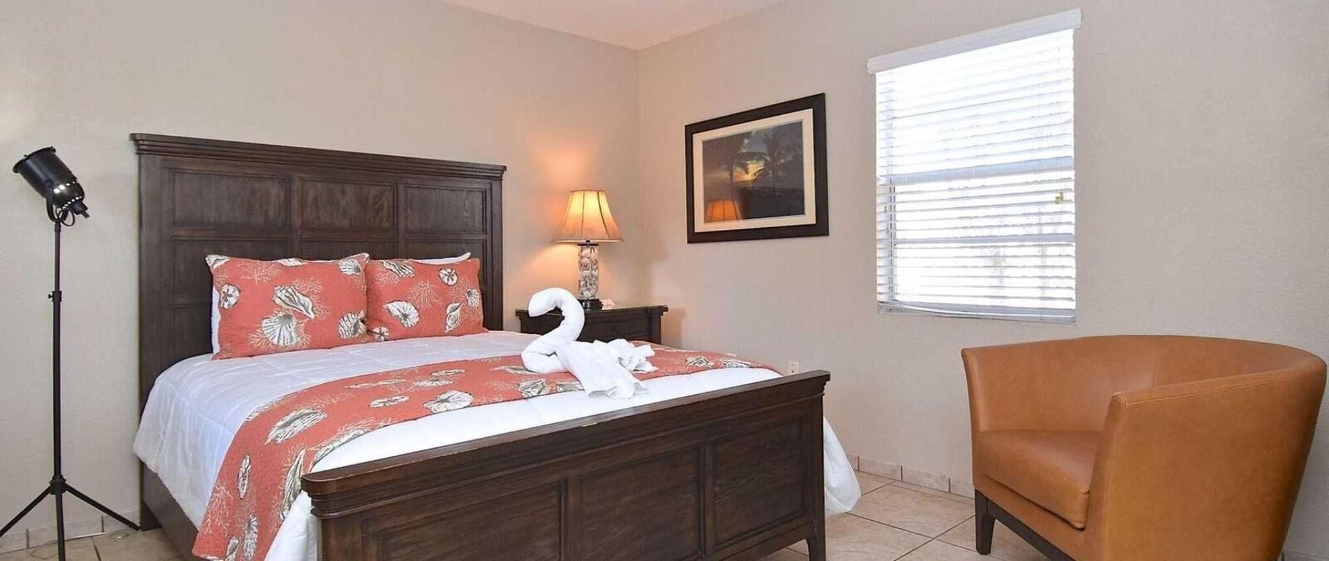 A bedroom with a bed , chair , lamp and window.