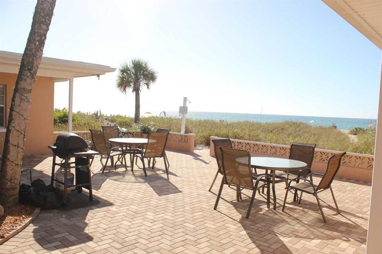 A patio with tables and chairs and a grill overlooking the ocean