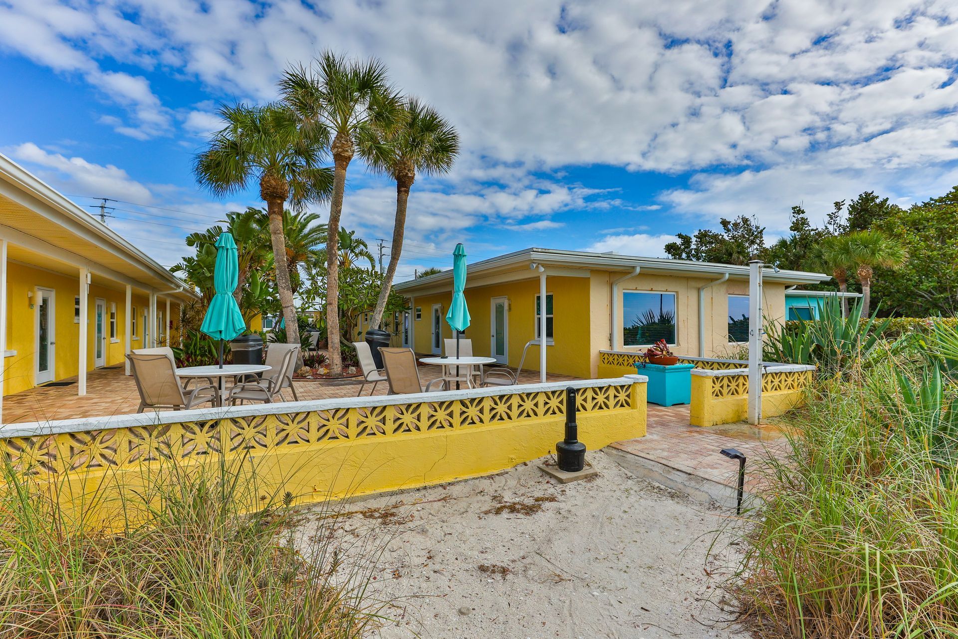 A yellow house with blue umbrellas in front of it