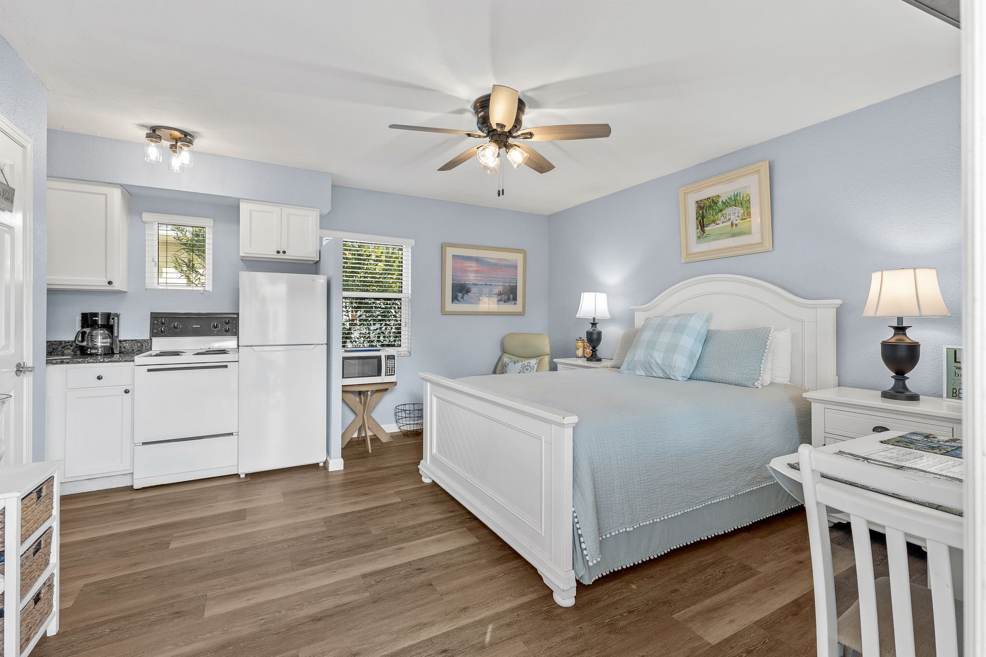 A bedroom with a king size bed, a kitchen, and a ceiling fan.