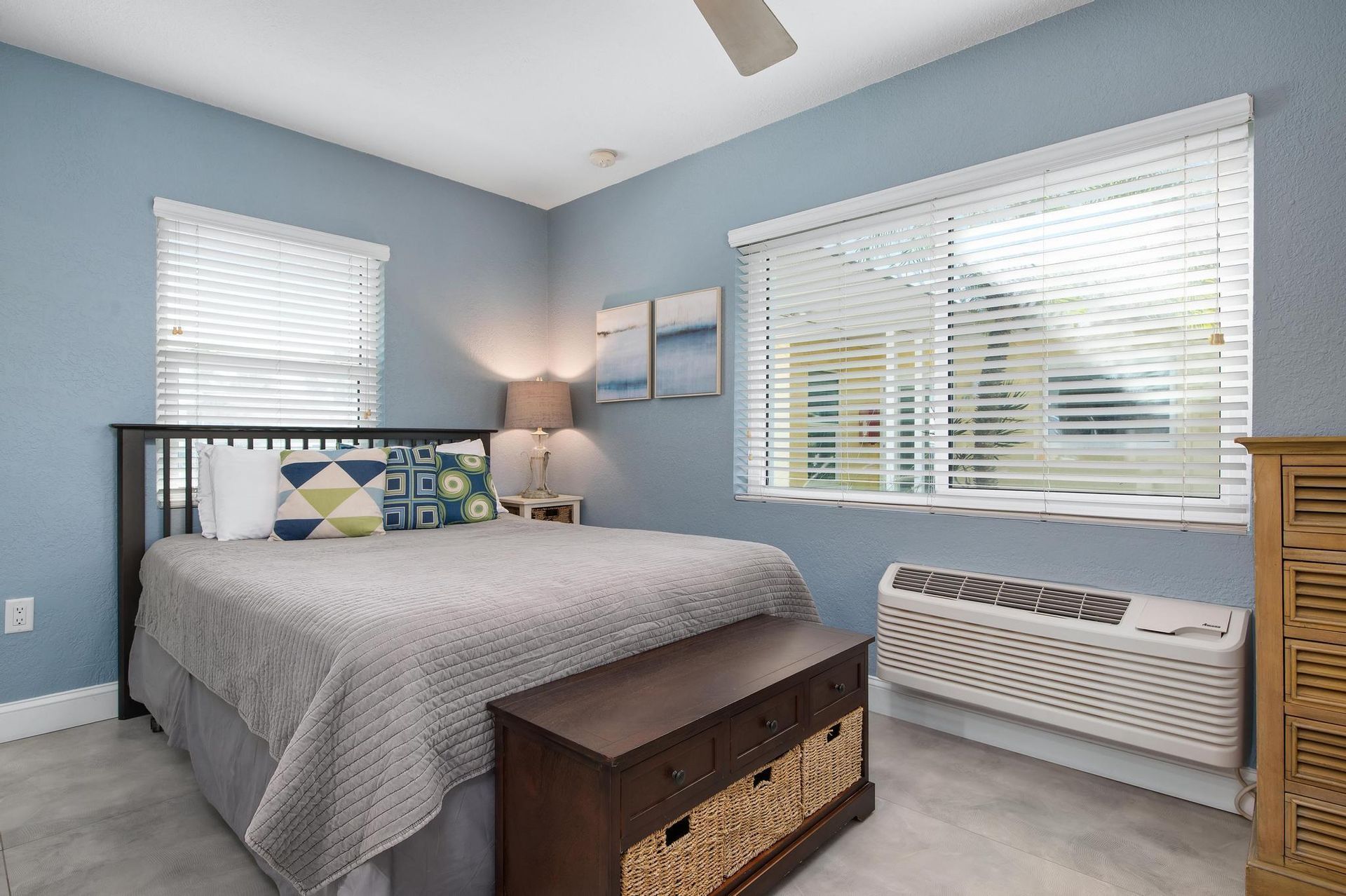 A bedroom with a bed, dresser, window and ceiling fan.