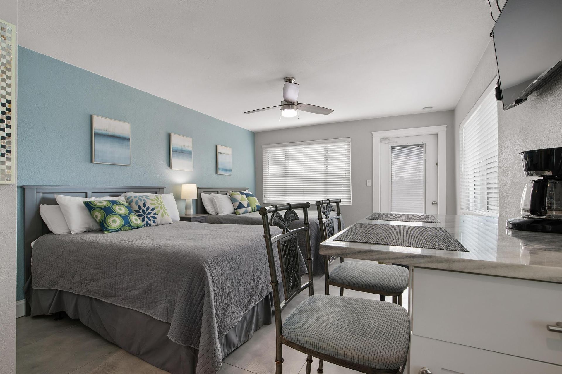 A hotel room with two beds, a table and chairs.