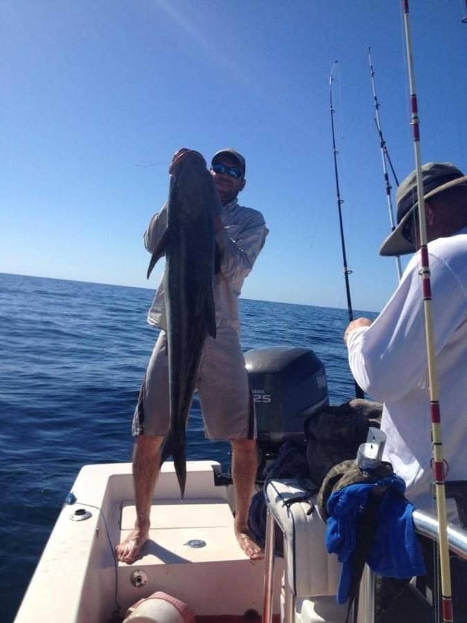 A man is holding a large fish on a boat in the ocean.