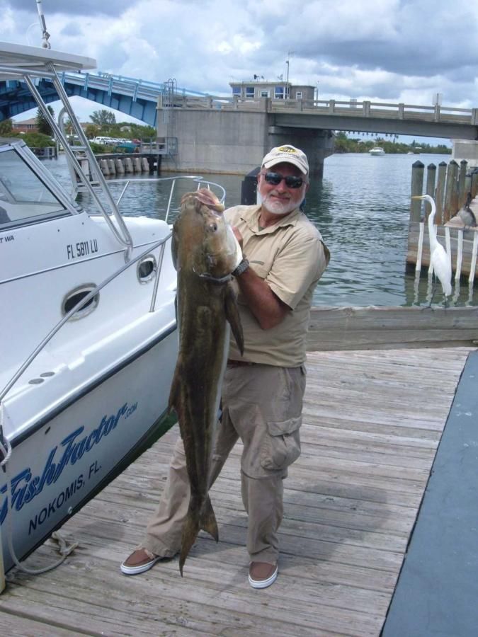A man is holding a large fish in front of a boat that says florida