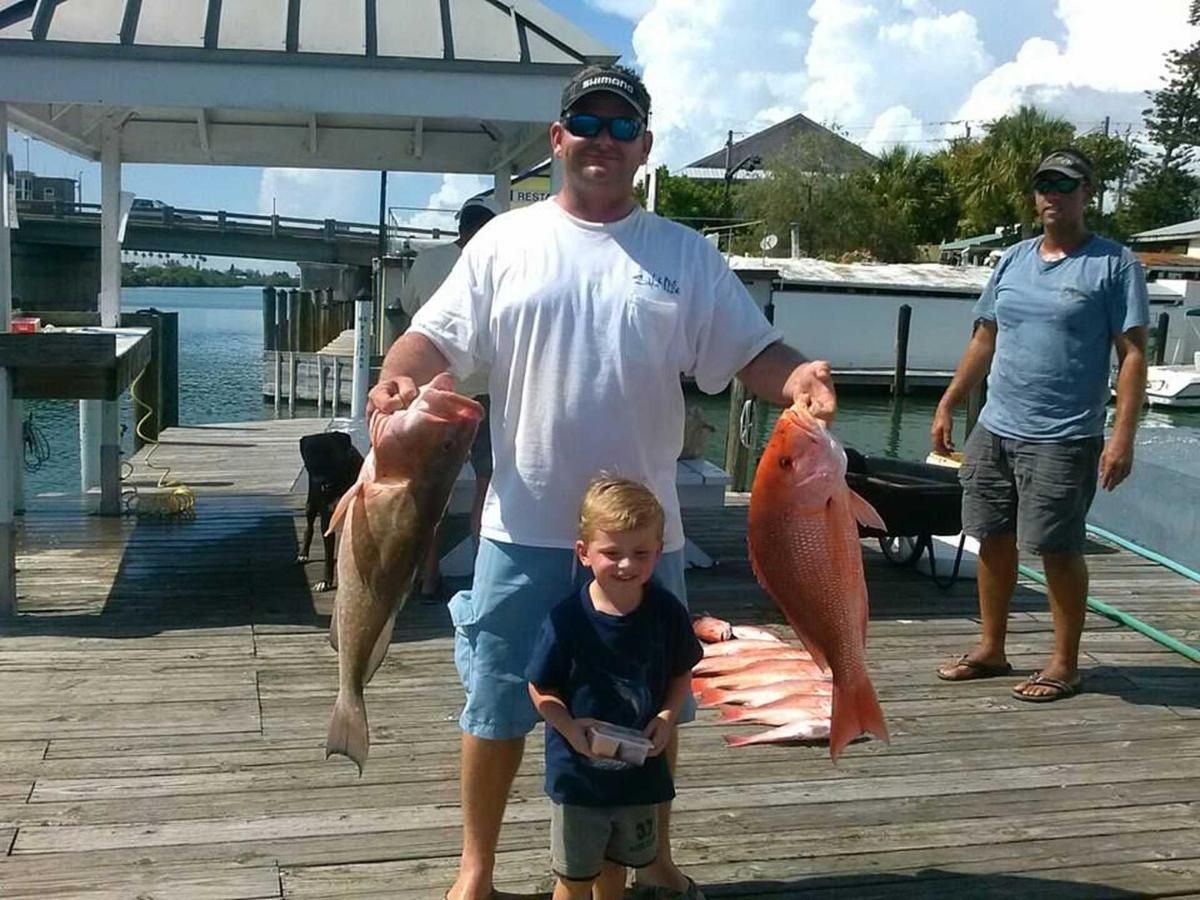 A man and a boy holding fish on a dock