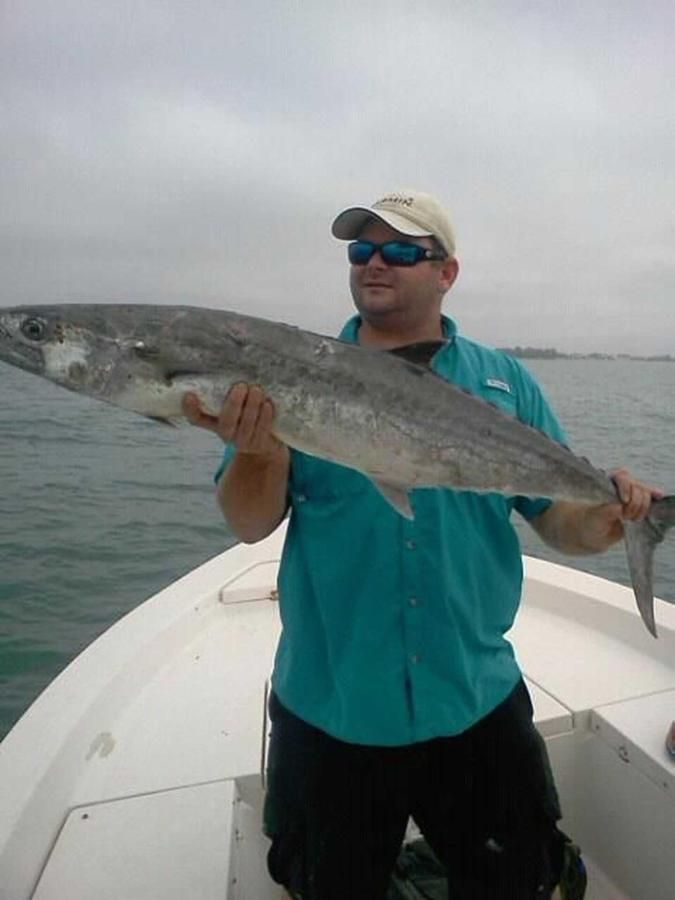 A man is holding a large fish on a boat.
