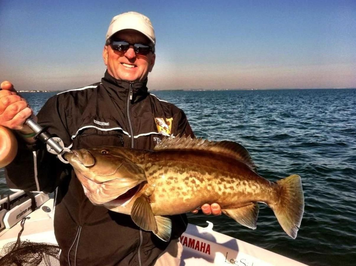 A man is holding a large fish on a boat.