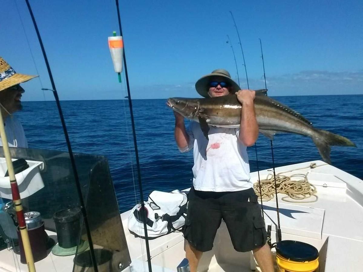 A man is holding a large fish on a boat