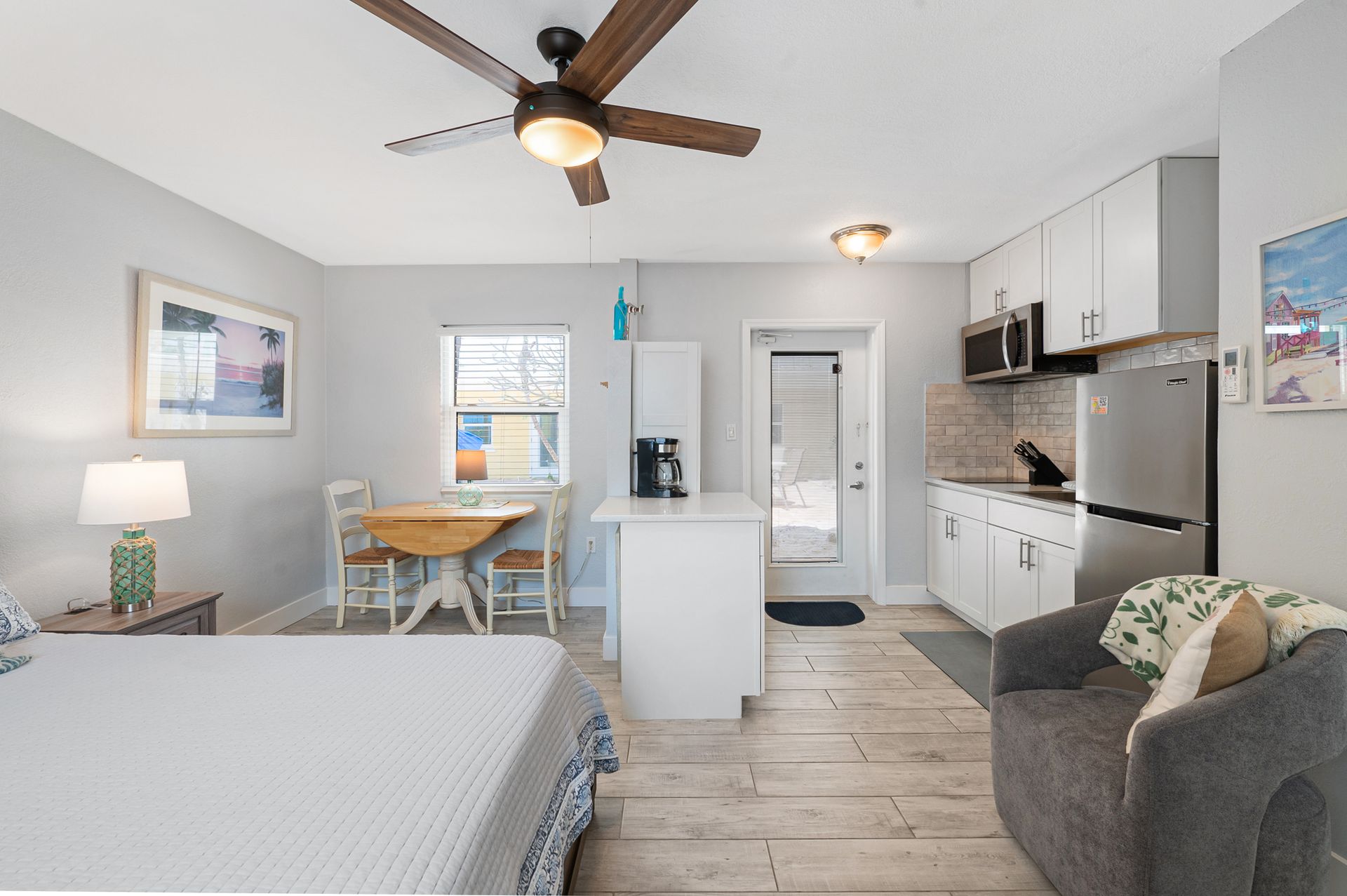 A bedroom with a bed , chair , table and ceiling fan.
