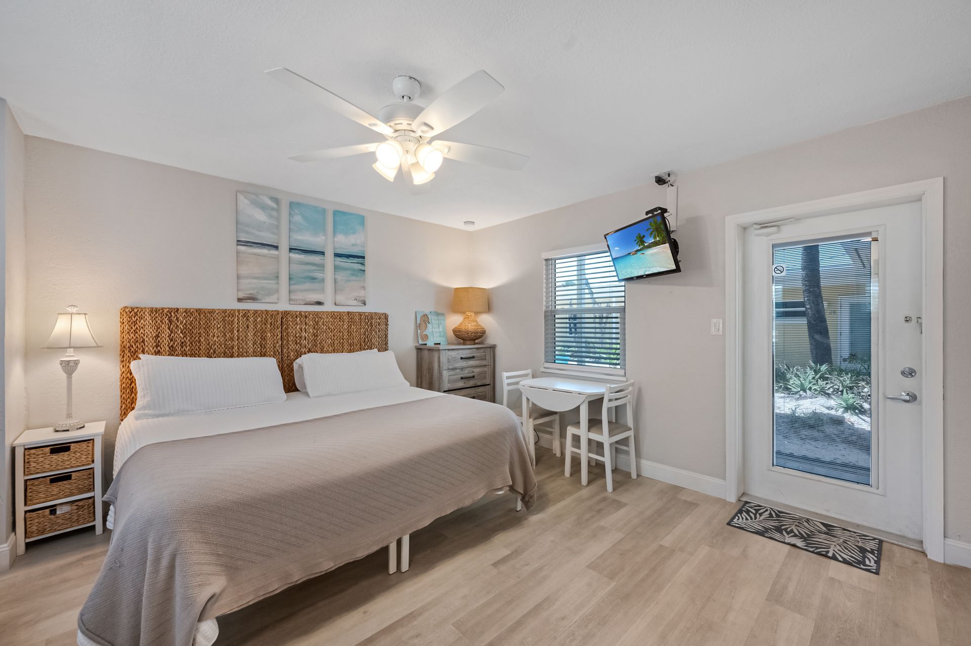 A bedroom with a king size bed , a desk , a television and a ceiling fan.