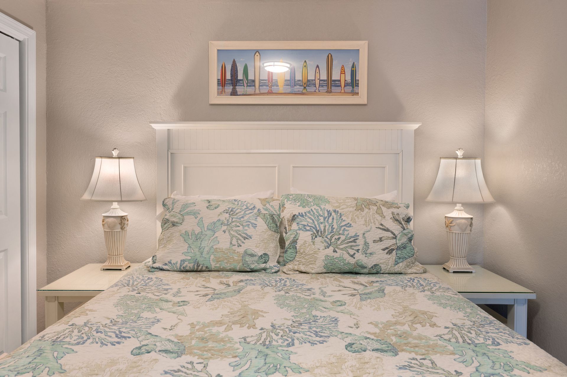 A bedroom with a bed , two lamps , and a picture on the wall above the bed.