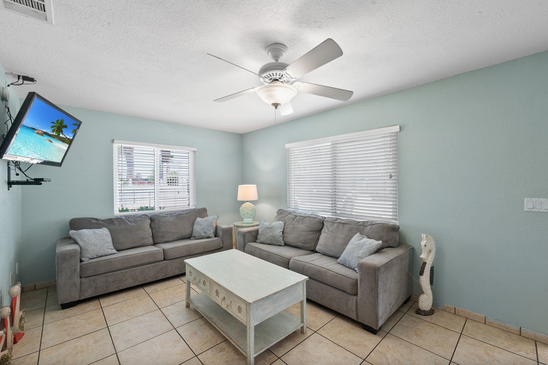 A living room with two couches , a coffee table , a television and a ceiling fan.