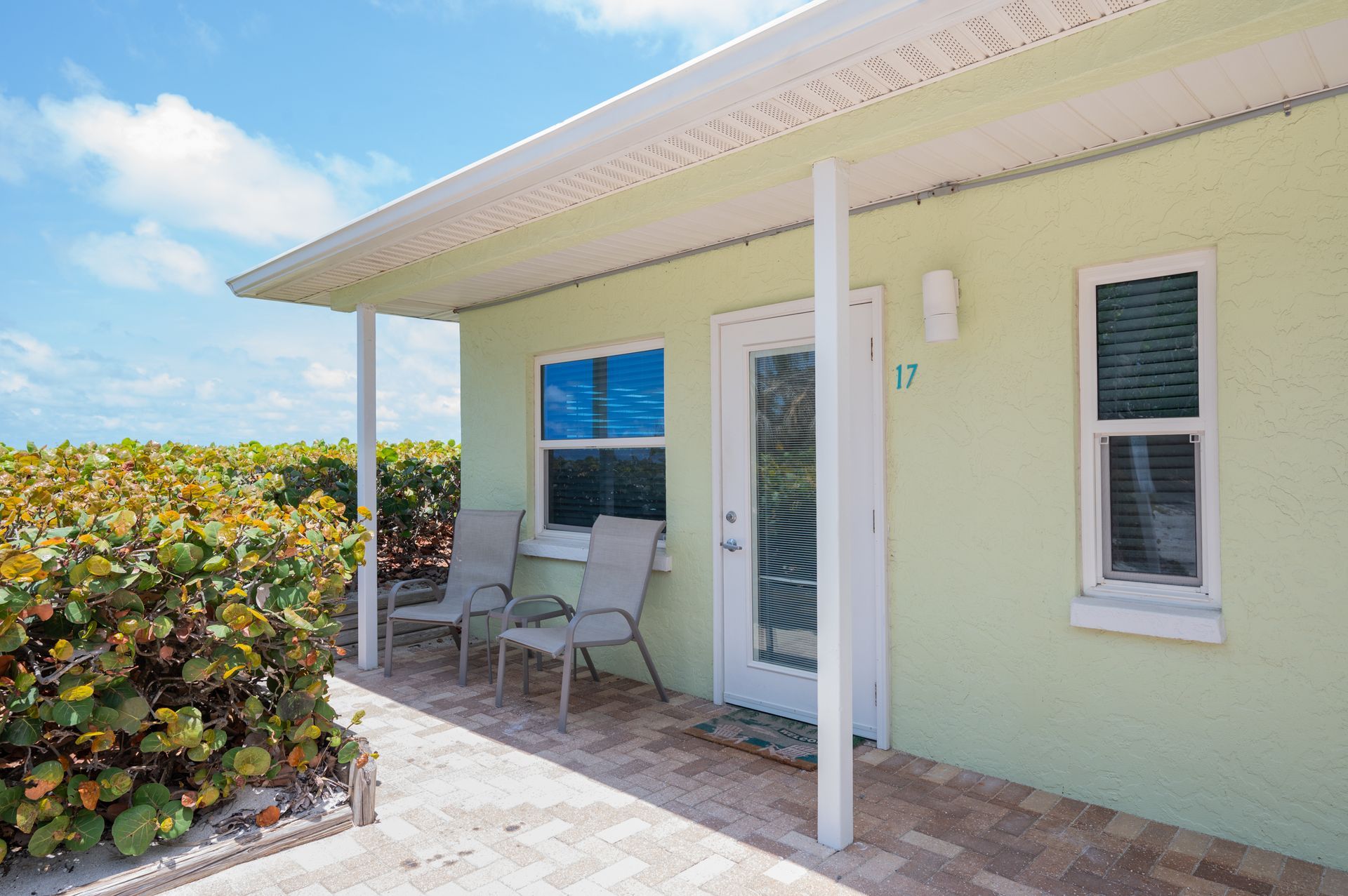 A small house with a porch and chairs in front of it.