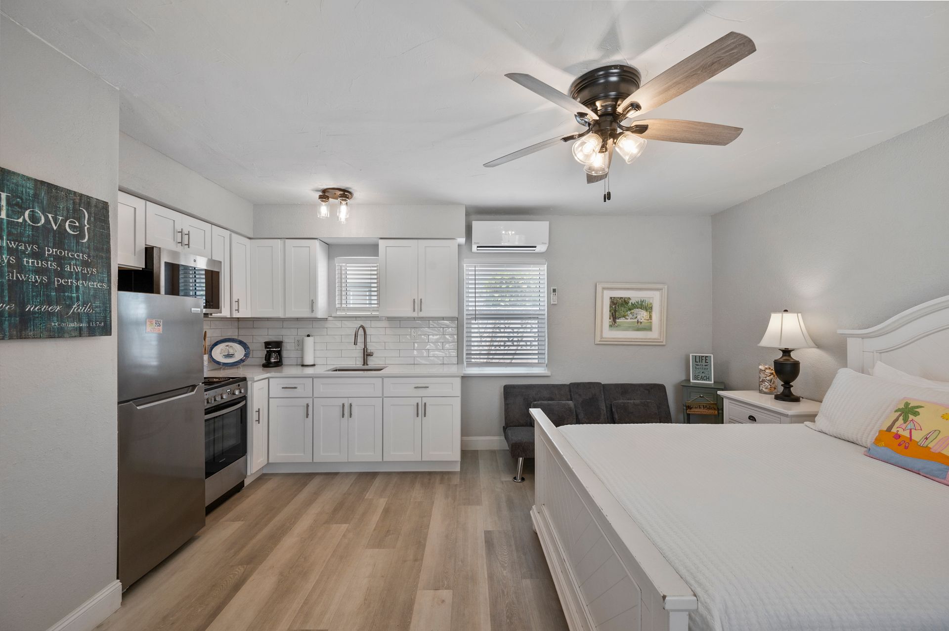 A bedroom with a king size bed , a kitchen , and a ceiling fan.