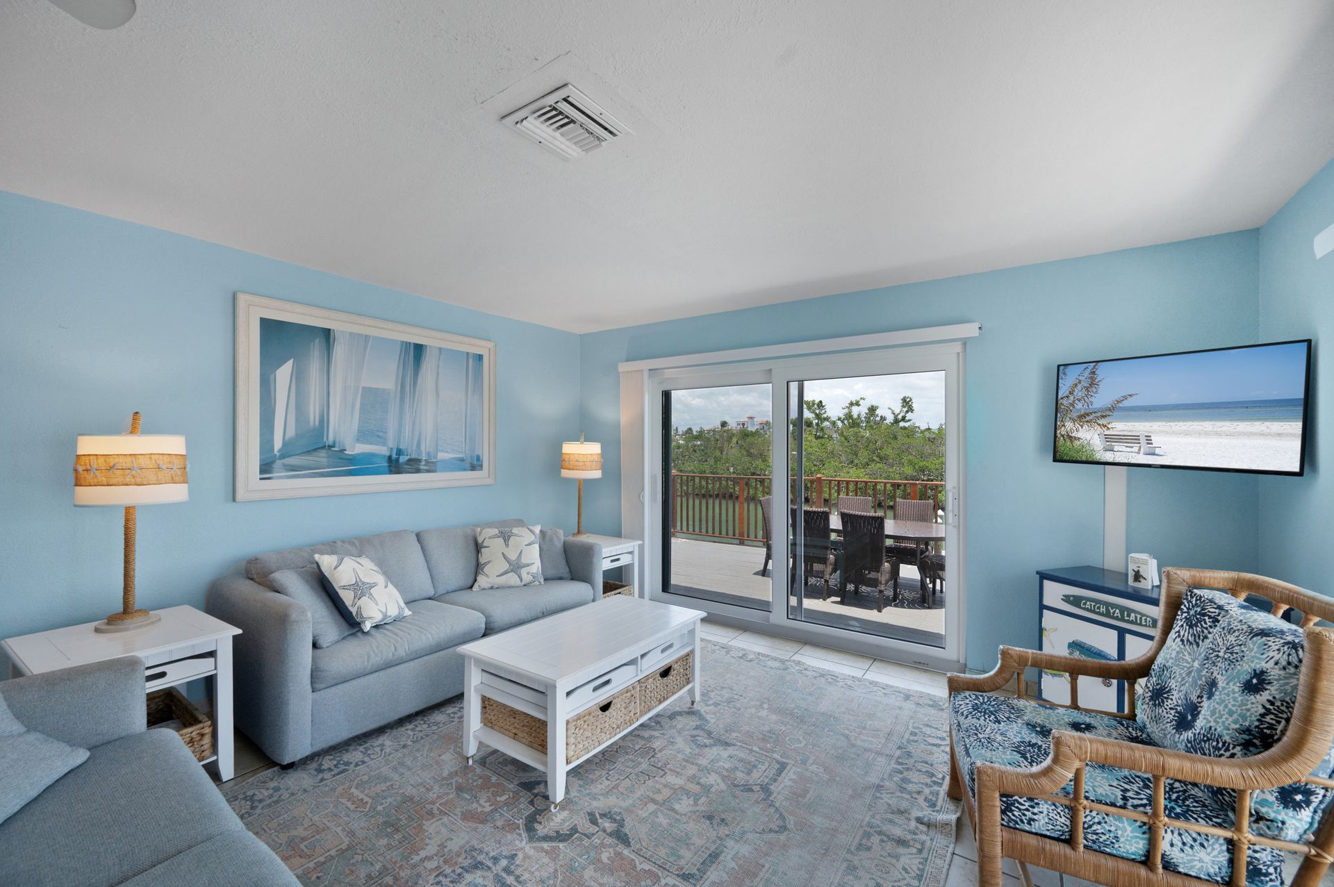 Bright living room with blue walls, sofa, and sliding glass door to outdoor deck.
