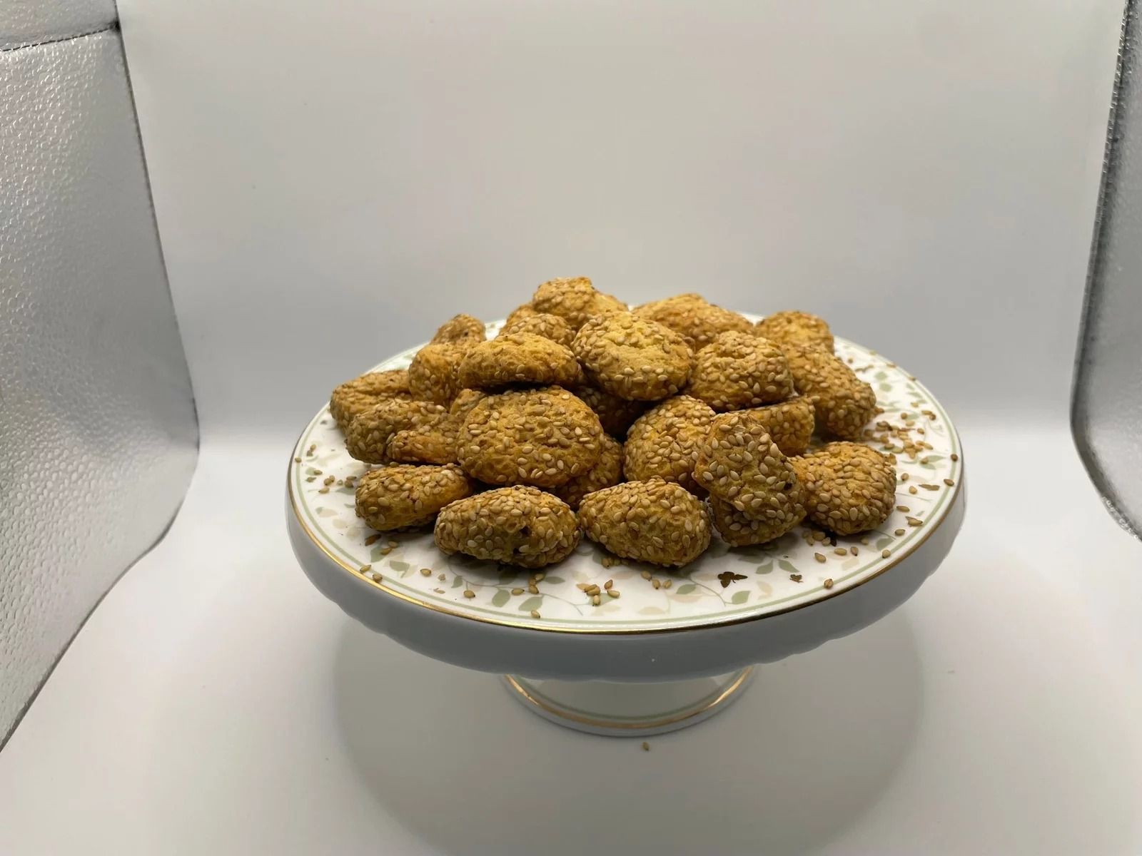 Mucchio di cibo fritto su un piatto decorativo con piedistallo, posto su uno sfondo semplice.