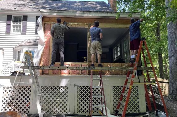 Remodeling: A group of men are working on the side of a house.