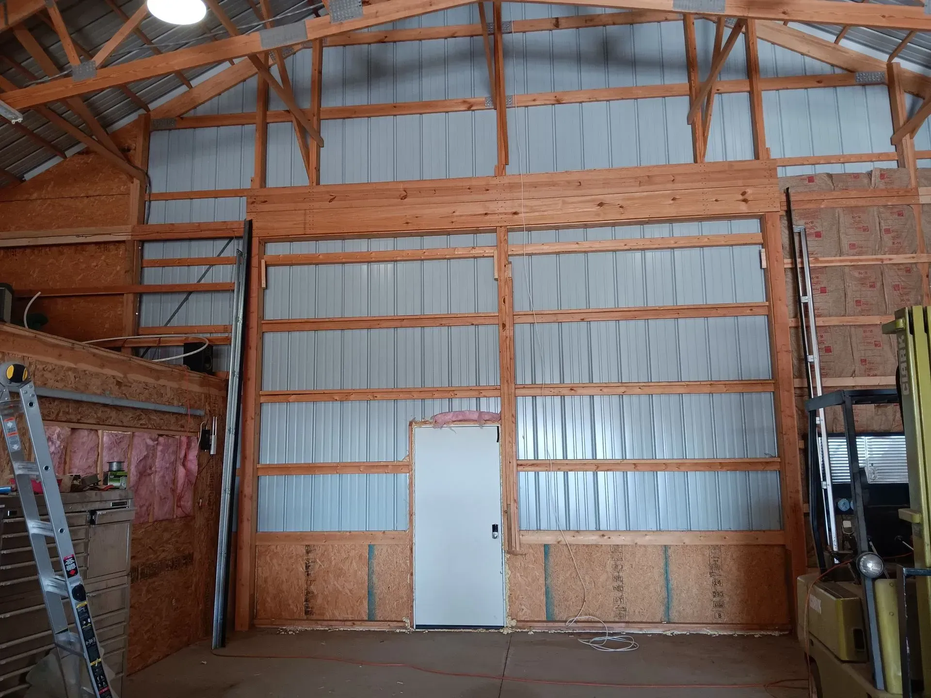 A large wooden barn with a white door and a ladder.