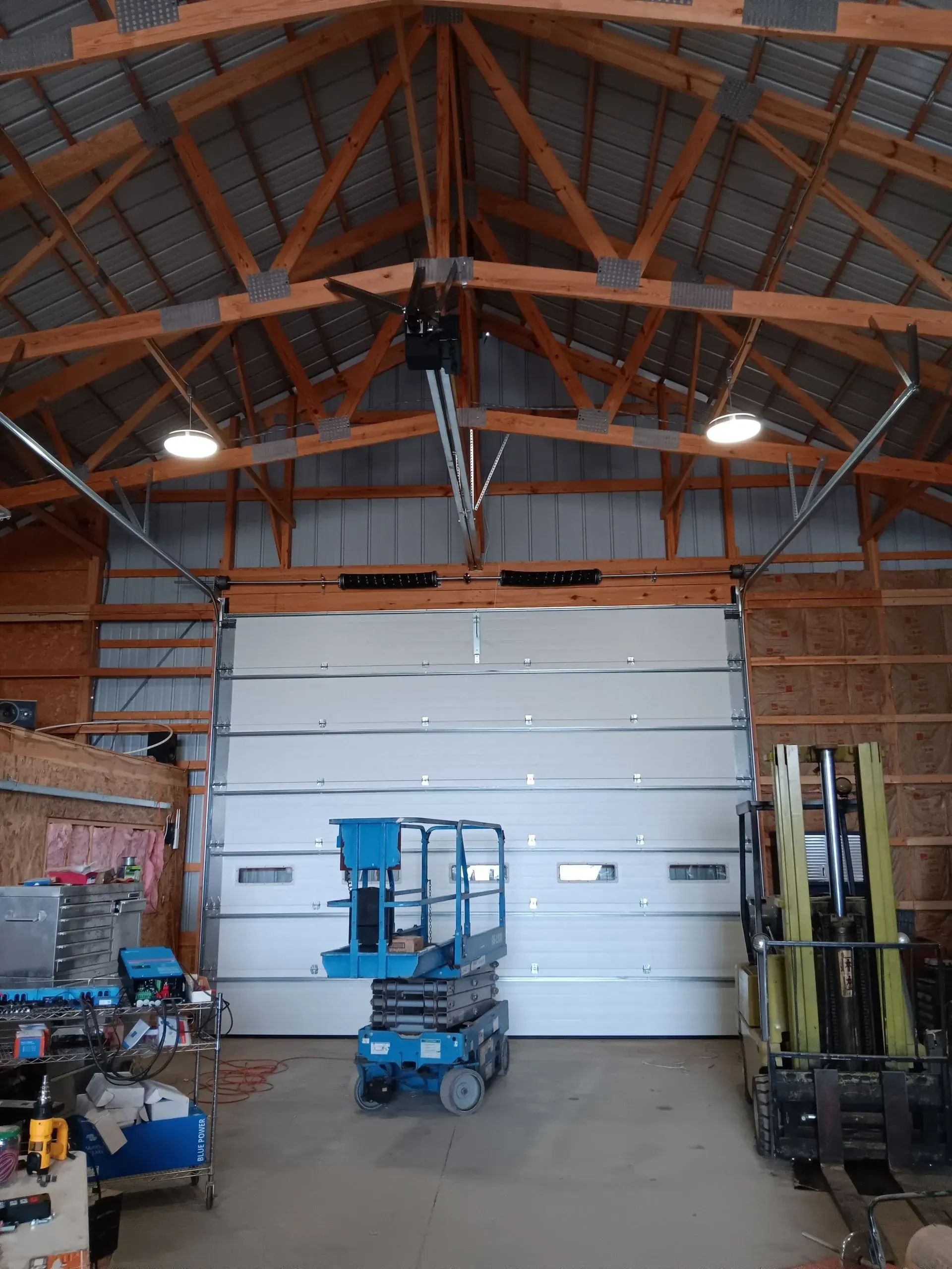 A garage with a large garage door and a forklift in it.