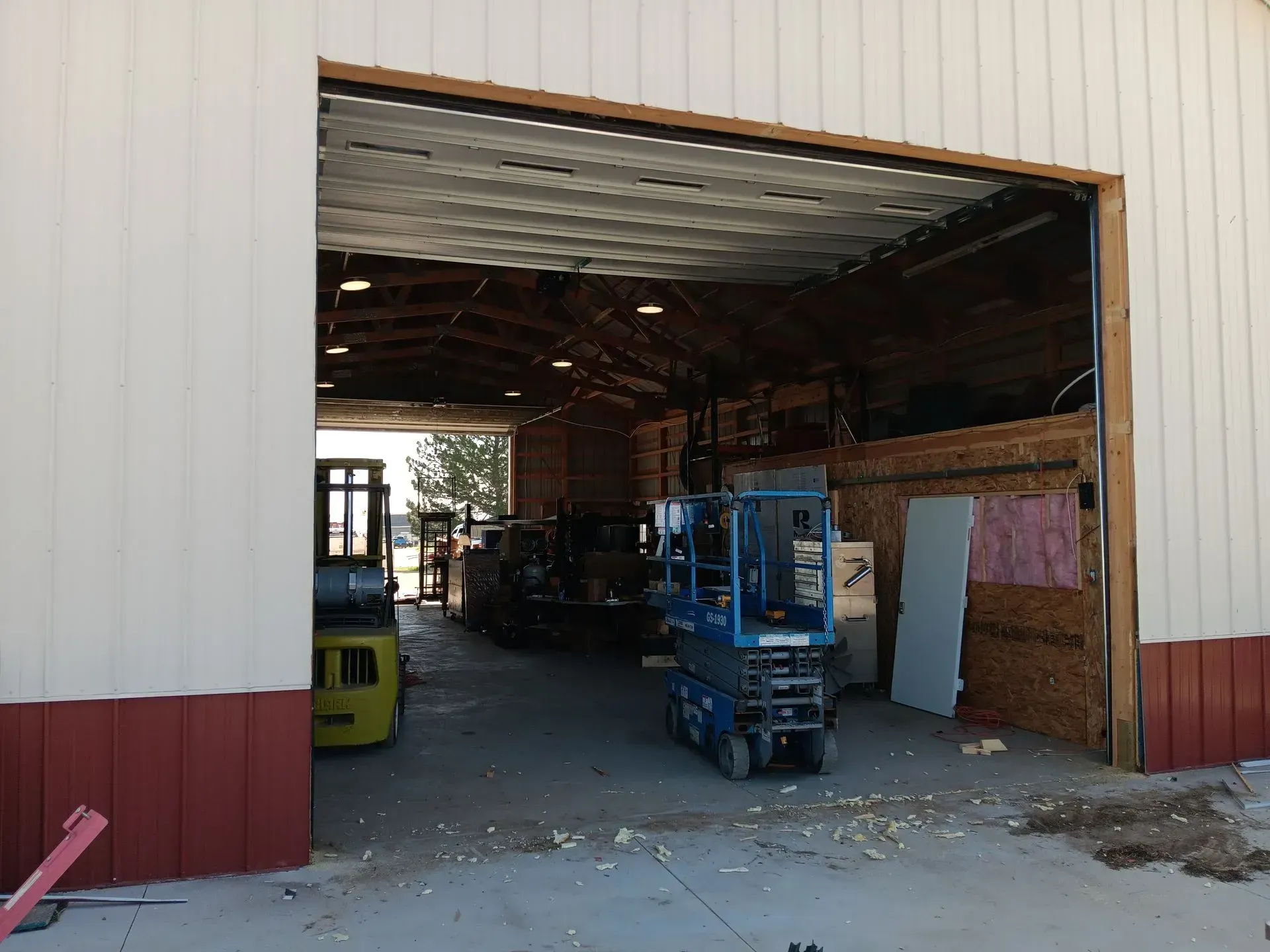 A warehouse with a forklift and a scissor lift in it