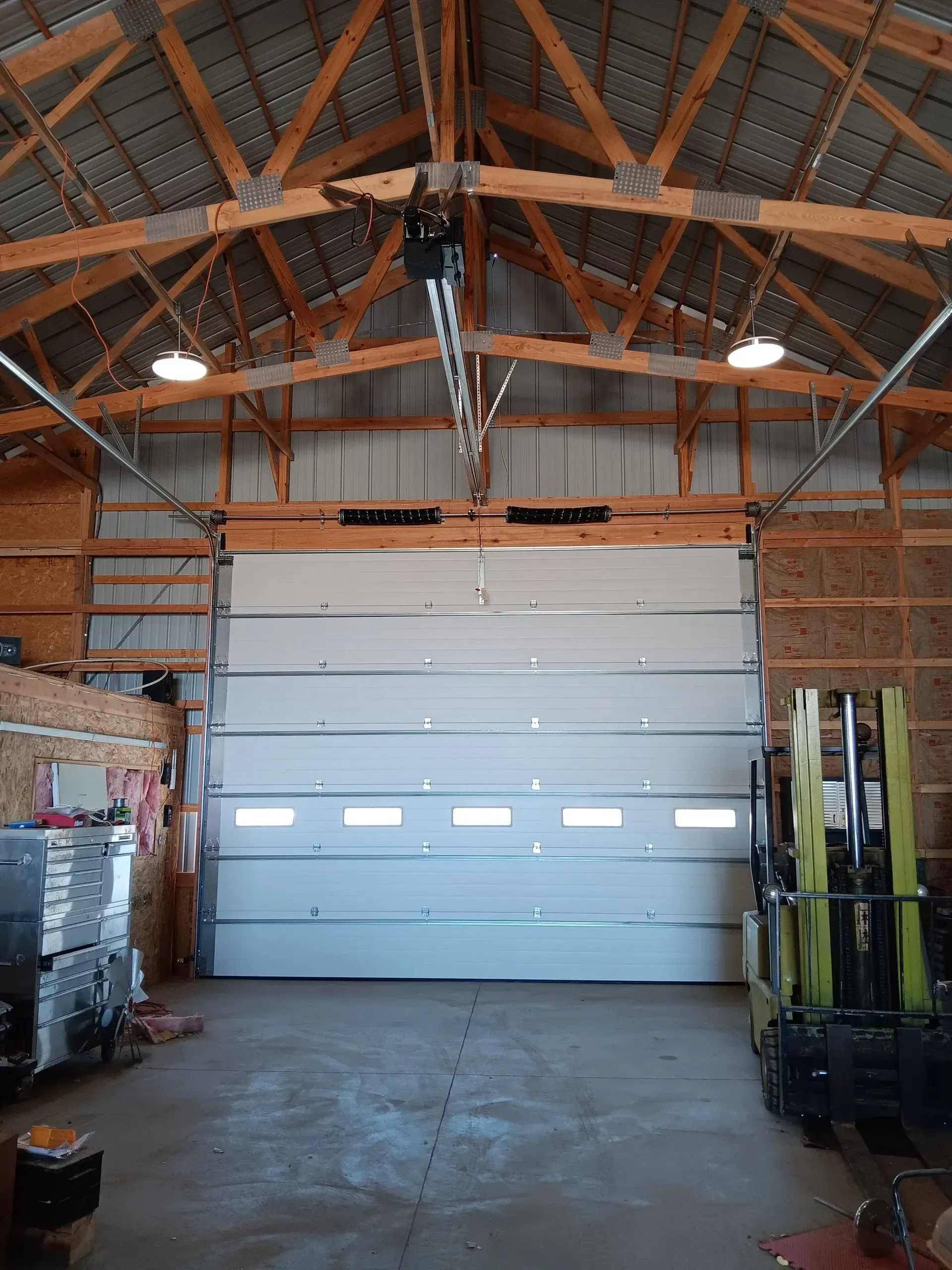 A man is standing on a ladder fixing a garage door.