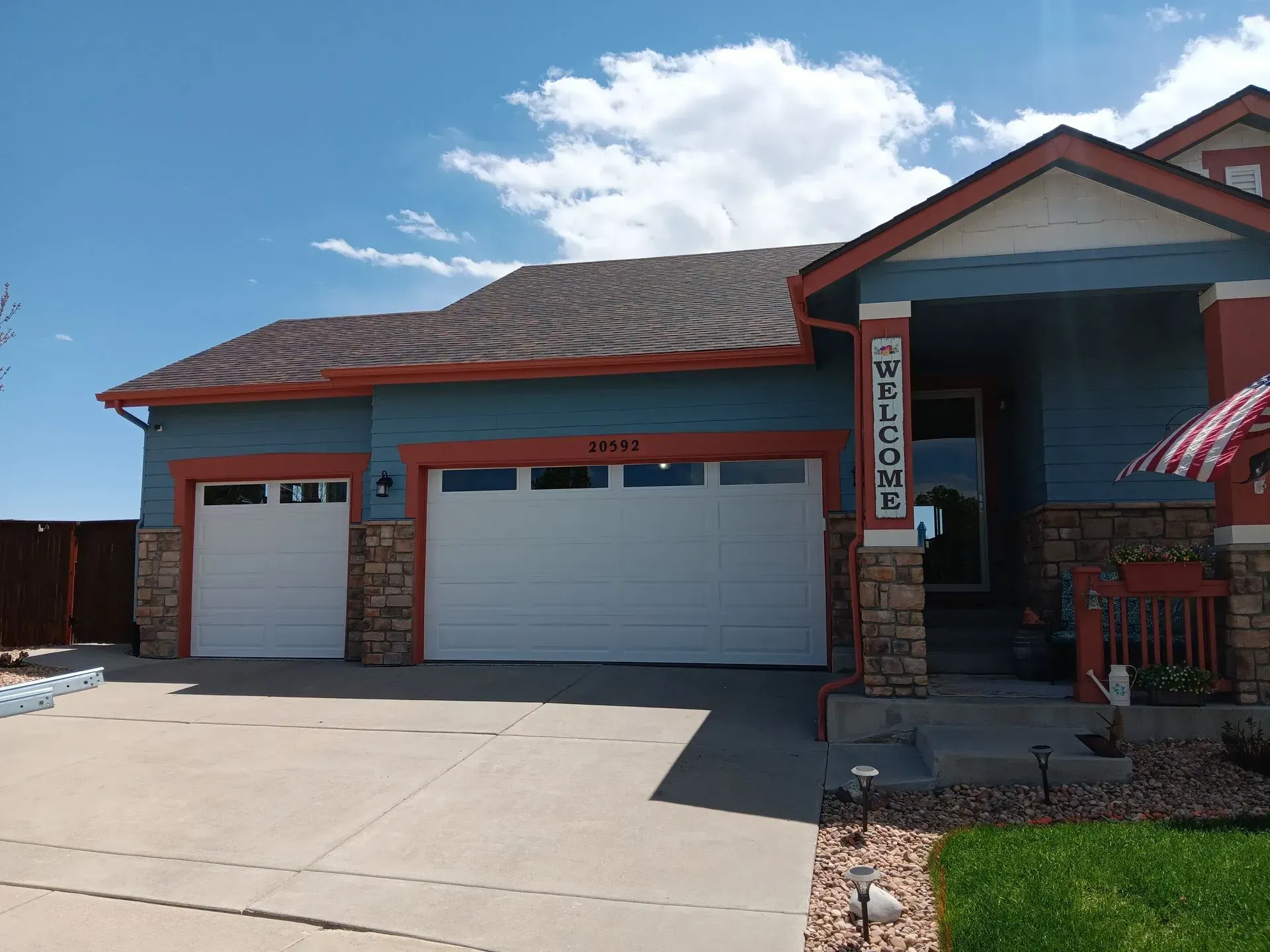 A blue and red house with two white garage doors