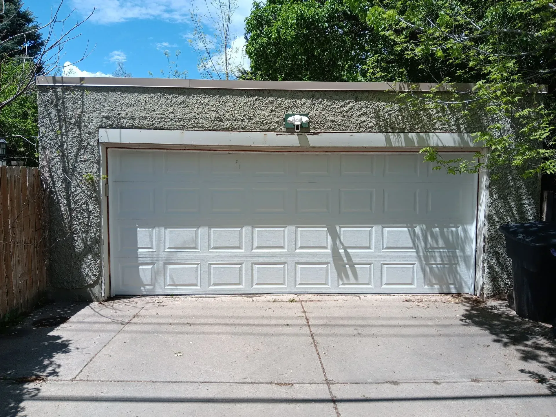 A white garage door with a concrete driveway in front of it