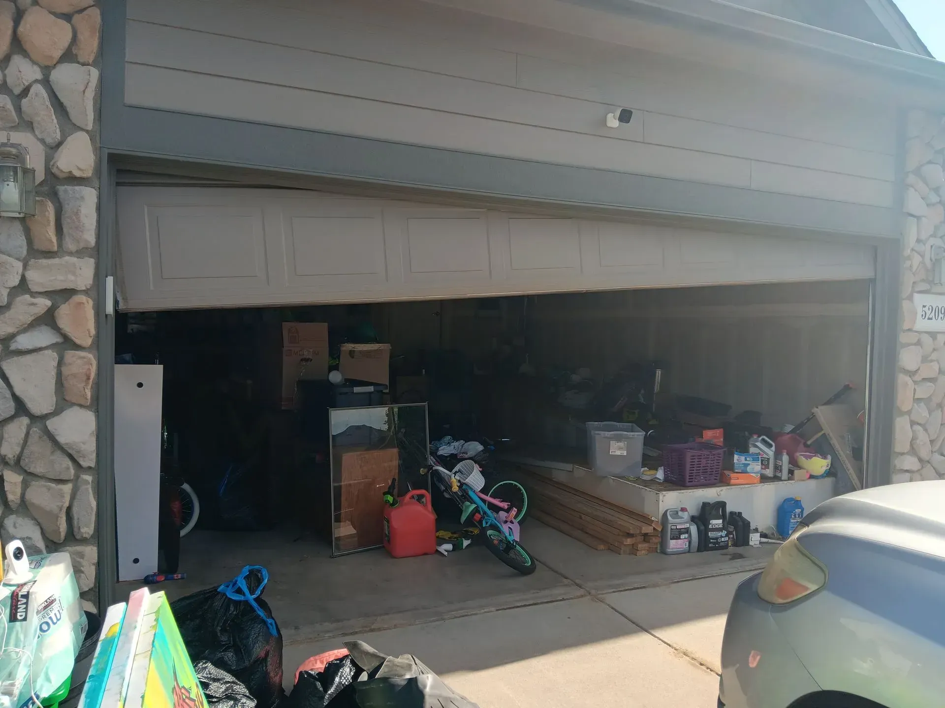 A garage filled with lots of junk and a car parked in front of it.