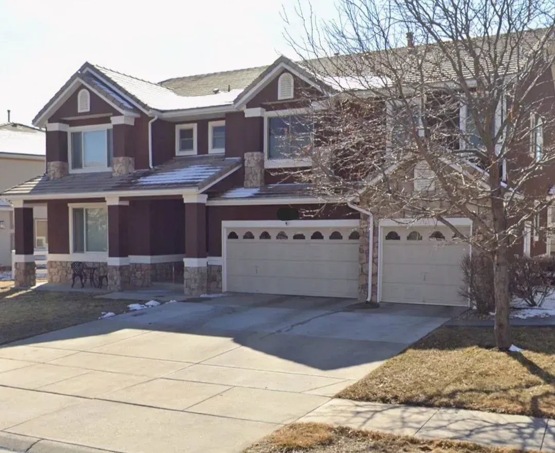 A large house with two garage doors and a tree in front of it
