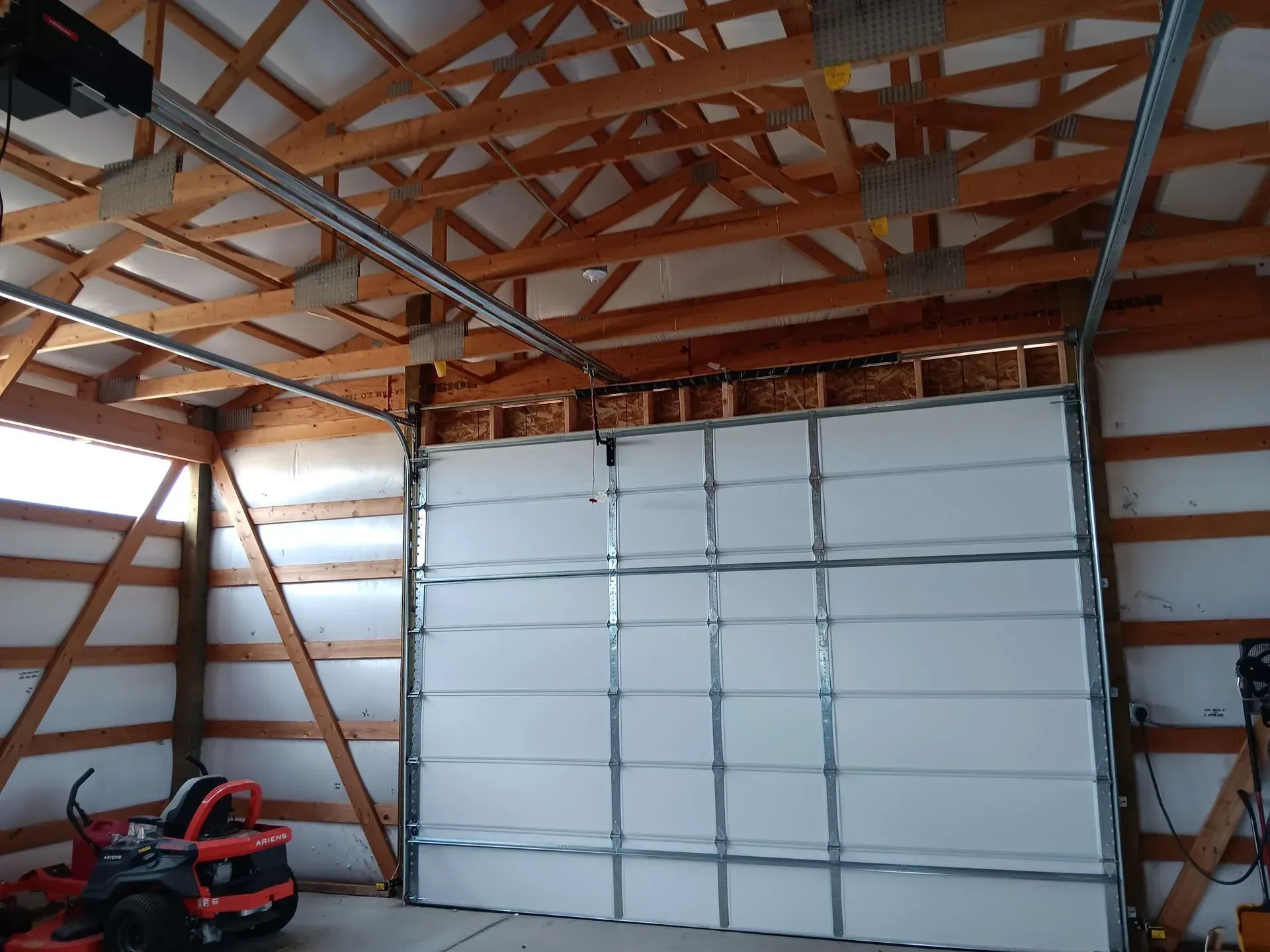 A garage with a large white garage door and a snow blower.