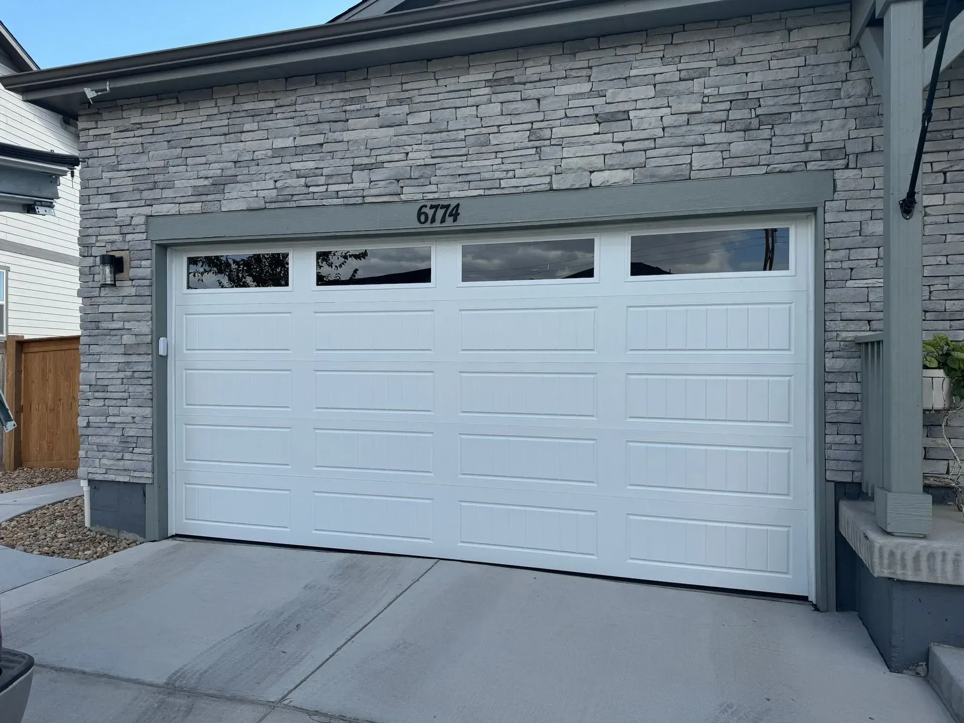 A white garage door is sitting in front of a brick building.