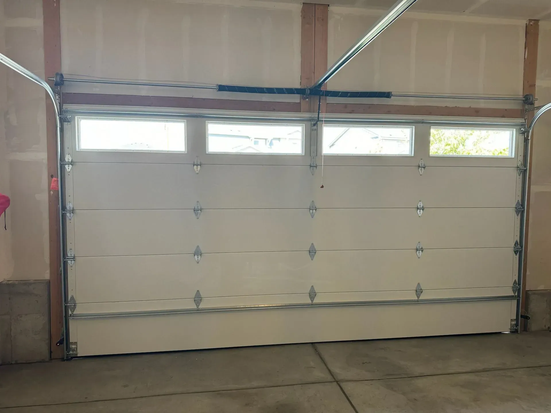 A man is standing on a ladder fixing a garage door.