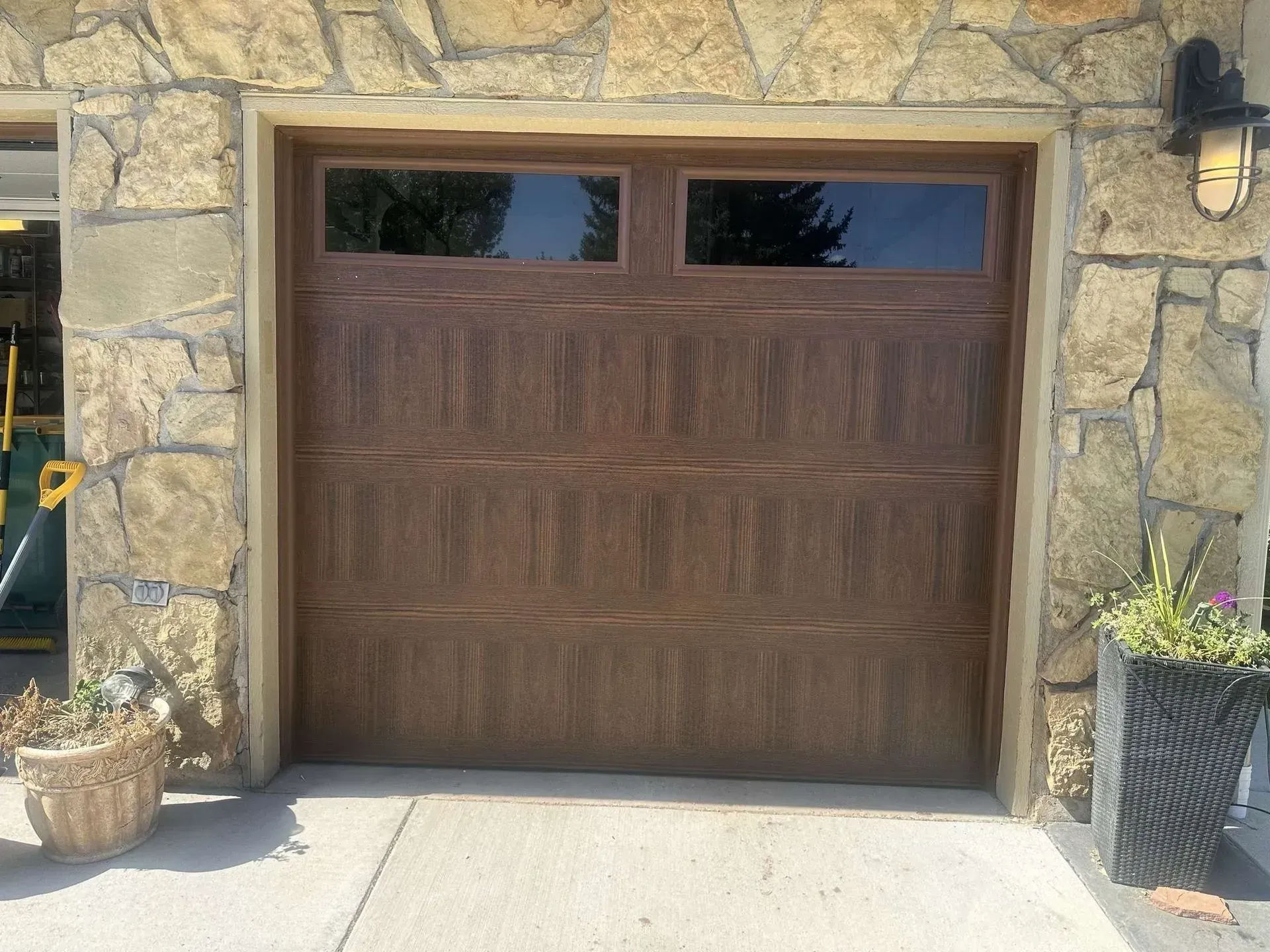 A wooden garage door with a stone wall behind it