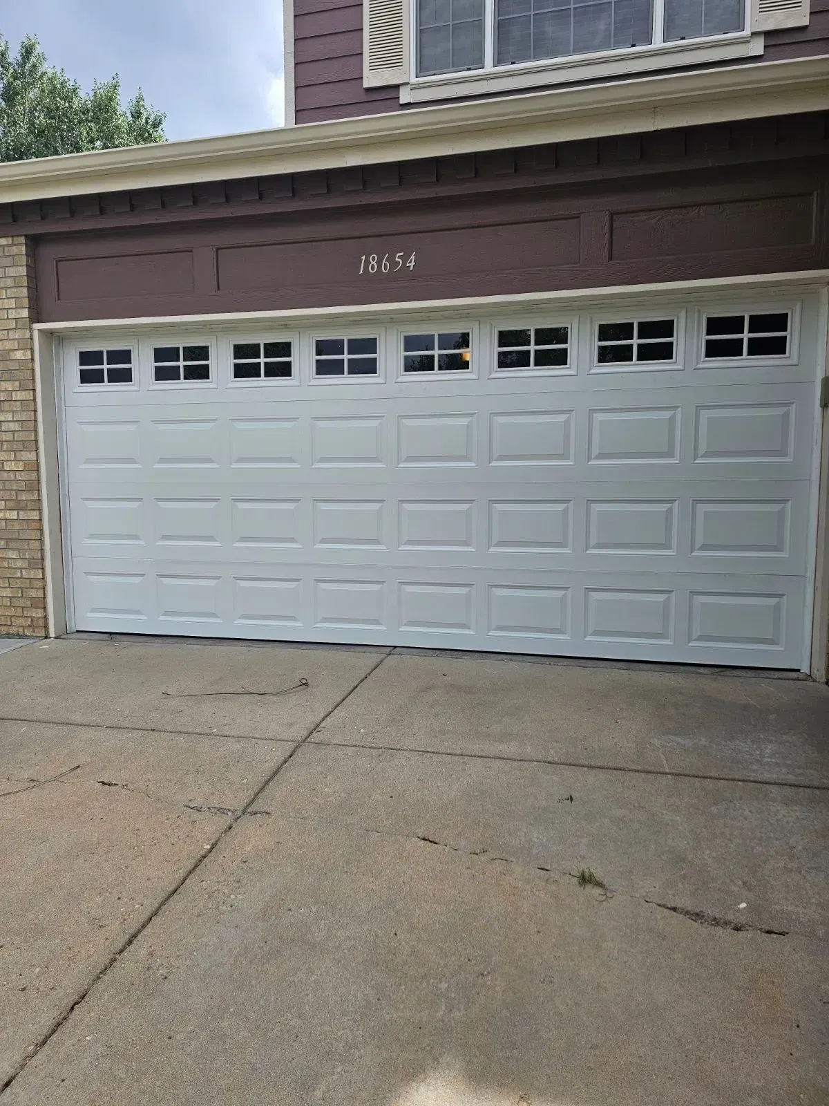 A white garage door is sitting in front of a house.
