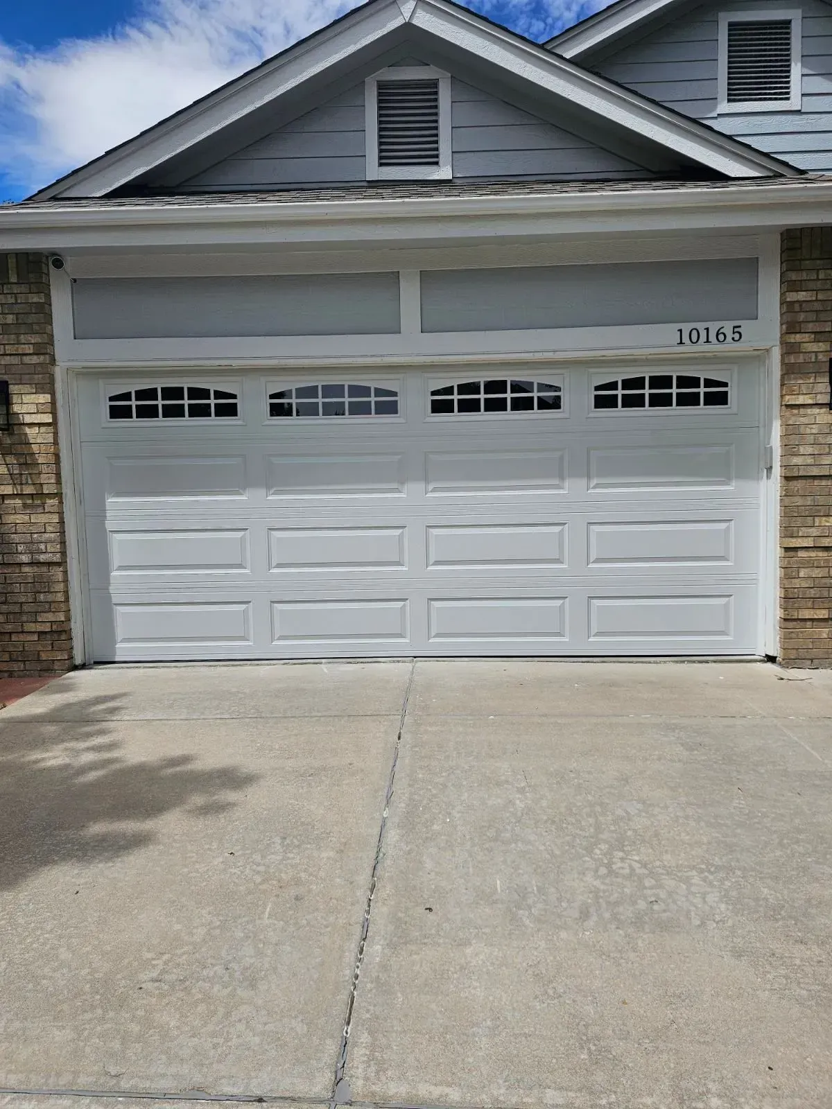 A white garage door is sitting in front of a house.