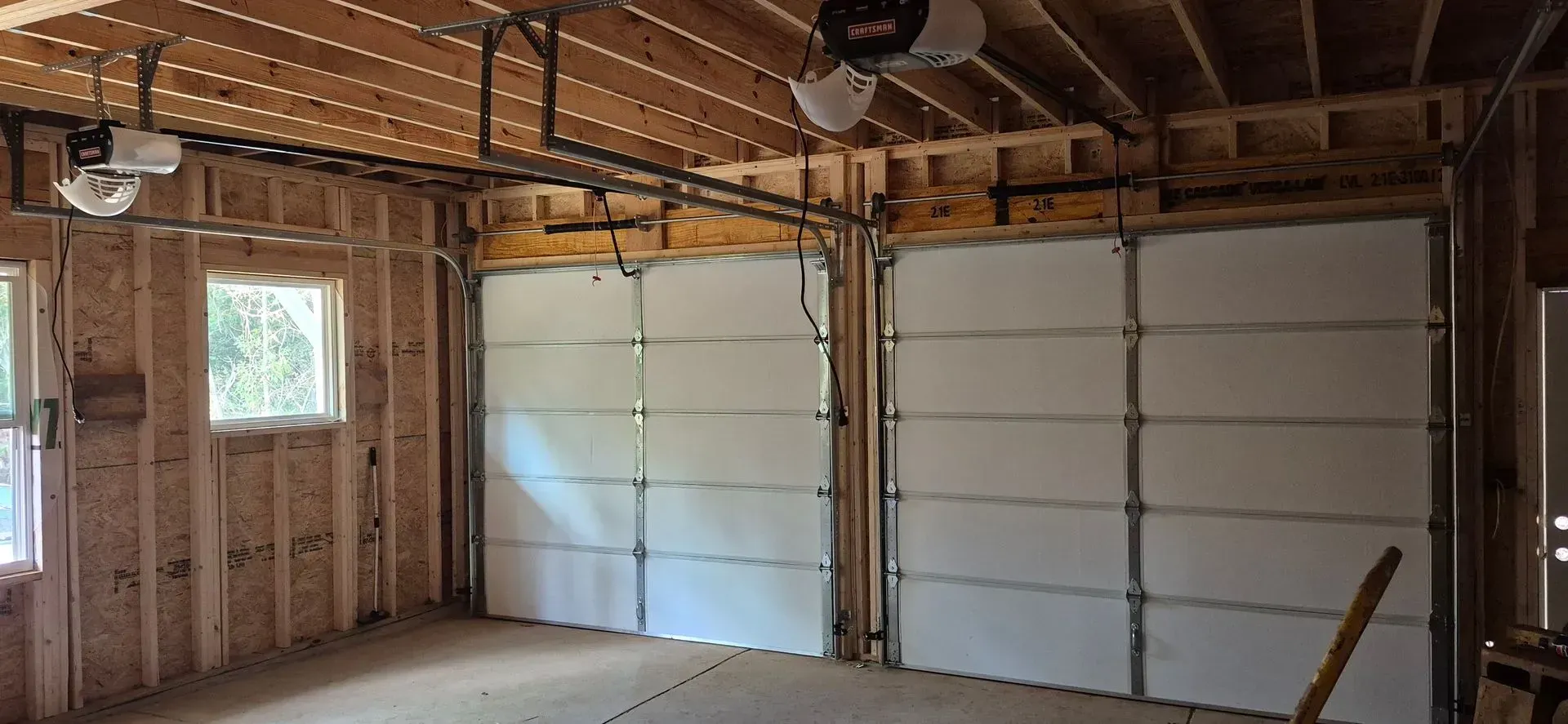 A garage with two garage doors and a fan on the ceiling.